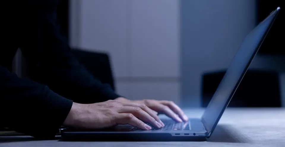 Close up on man hand type on keyboard laptop to check about programming of security system software in the dark operation room for internet and…