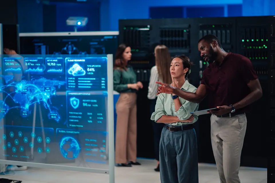 It experts collaborating, analyzing global network information and cloud resources on an interactive screen in a secure data center