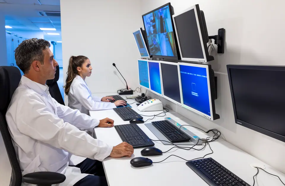 Male and female MRI technicians monitor patients on monitors
