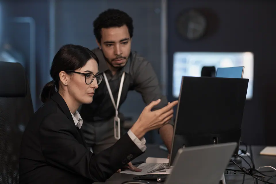 Portrait of senior project manager pointing at computer screen while reviewing code in office