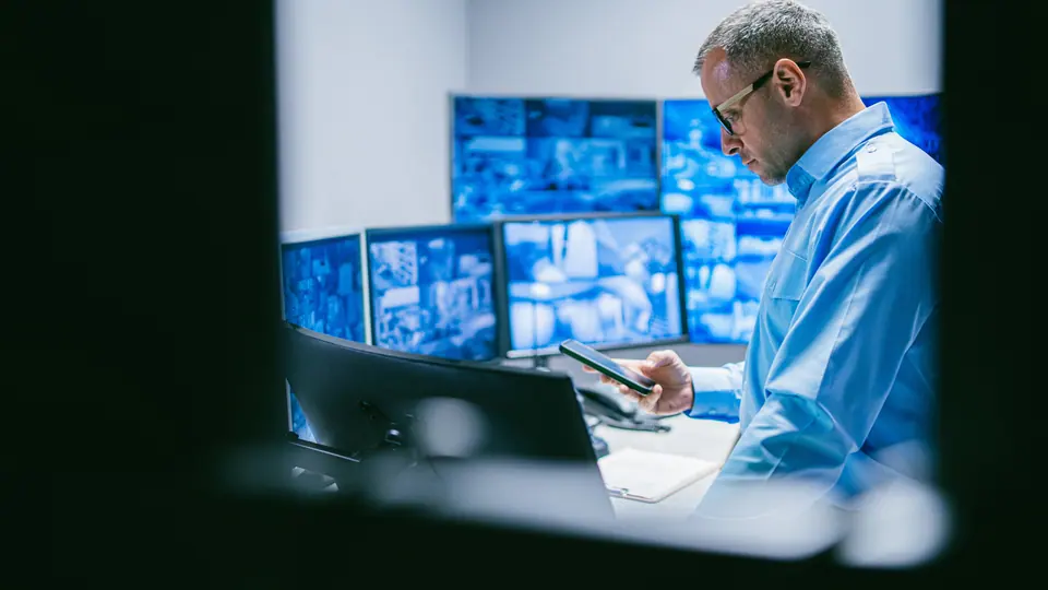 Security male operator reviewing data in control room with technology