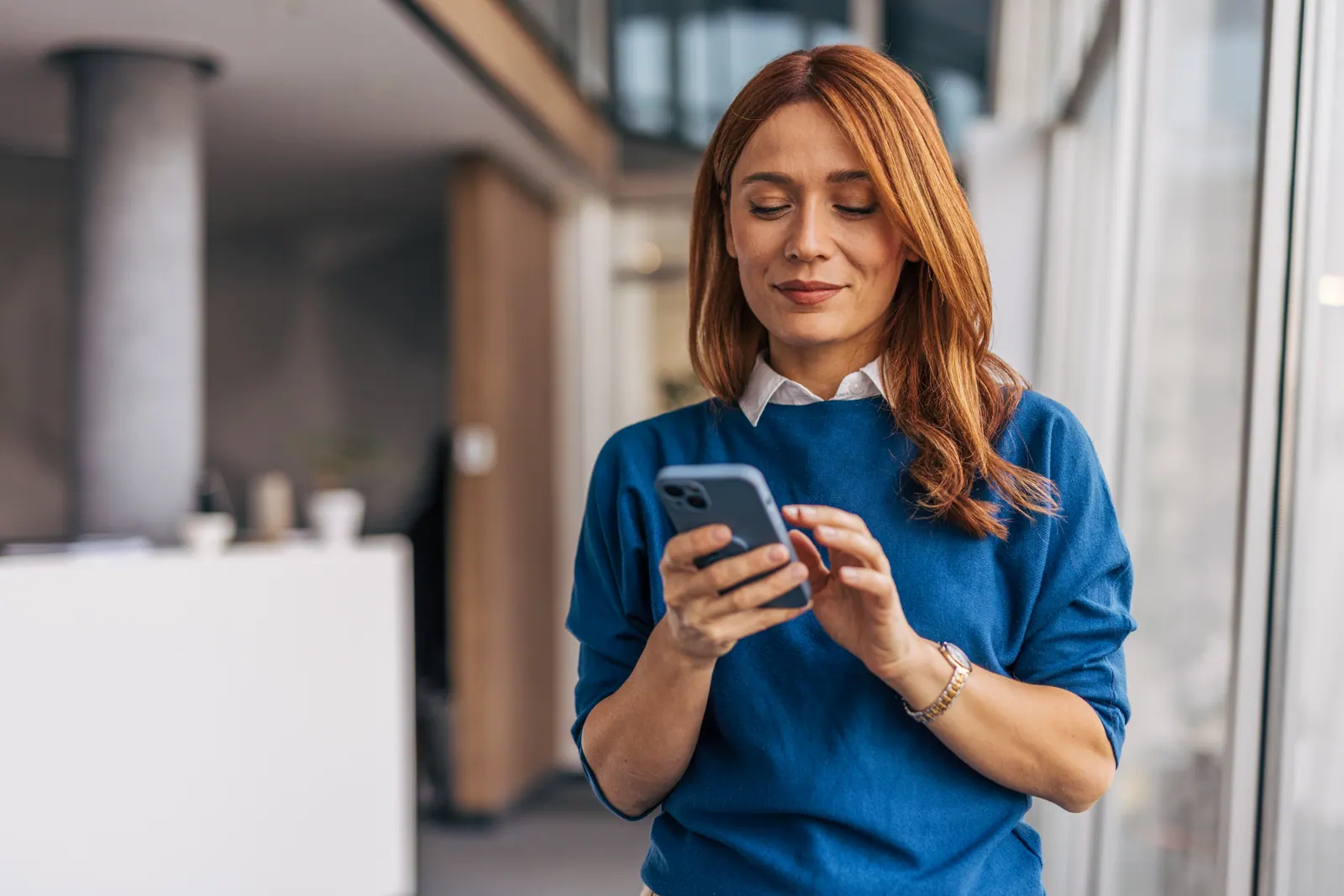 Woman in a blue top using a mobile phone outdoors